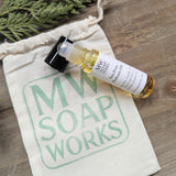 A roller bottle of natural perfume oil rests on a muslin bag stamped with the MW Soapworks logo.