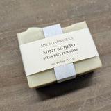A 4 ounce bar of MW Soapworks Mint Mojito Shea Butter Soap sits on a wooden background.
