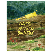 A belated birthday card features a watercolor banana slug crawling along a Pacific Northwest forest with mushrooms.