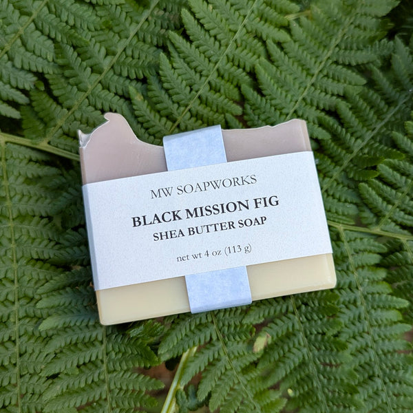 A four ounce bar of Black Mission Fig Shea Butter Soap from MW Soapworks sits on a bed of Pacific Northwest ferns.