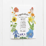A greeting card with watercolor illustrations of a rainbow of colorful flowers surrounds a coming out message. The text reads "Congratulations on having a new queer child/sibling/cousin/relative/friend. It's Me."