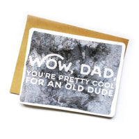 On a dark grey greeting card text reads "wow, dad, you're pretty cool for an old dude."