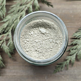 A jar of Deep Clean Clay Mask sits open, showing the light green color of the clays inside.