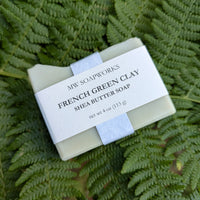 A four ounce bar of French Green Clay Shea Butter Soap from MW Soapworks sits on top of Pacific NW ferns.