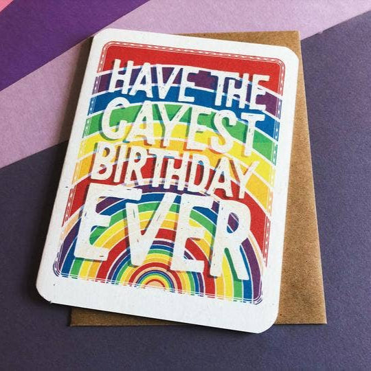 A rainbow greeting card has big block letters that read "have the gayest birthday ever."