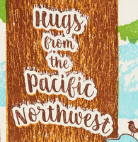 A close up of a greeting card shows the letterpress detail of a printed tree with the text "Hugs from the Pacific Northwest" on it.