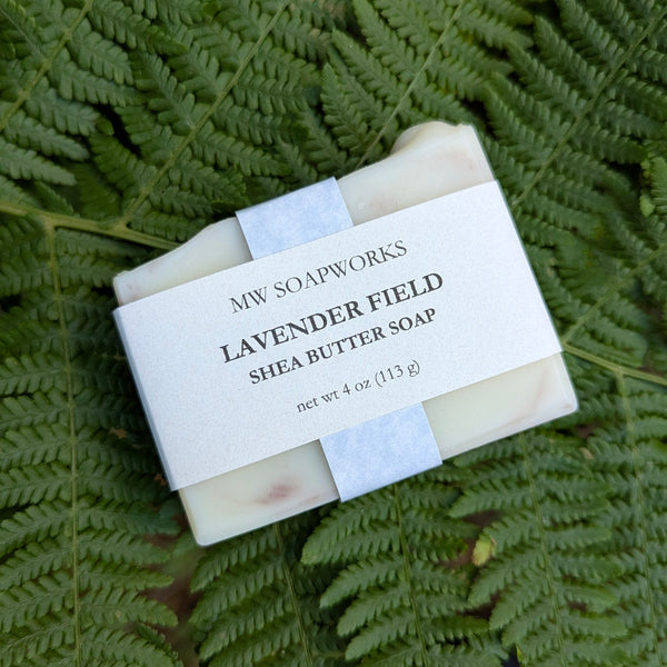 A four ounce bar of Lavender Field Shea Butter Soap from MW Soapworks sits on a Pacific Northwest fern background.