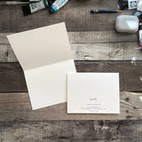 An open greeting card sits open while another shows the back. The inside is blank and the back shows the artist Yardia's logo and information.