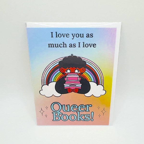 A greeting card features a cartoon queer cutie with a stack of books in front of a rainbow. The card says "I love you as much as I love Queer Books!"
