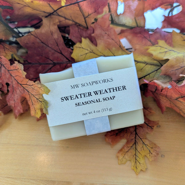 A bar of Sweater Weather Seasonal Soap from MW Soapworks sits on colorful fall leaves.