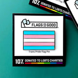 An enamel pin of the trans pride flag sits against a teal background. The label advertises that 10% of sales are donated to LGBTQ charities.