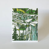 Image of a greeting card with a mountain waterfull blockprint art scene.