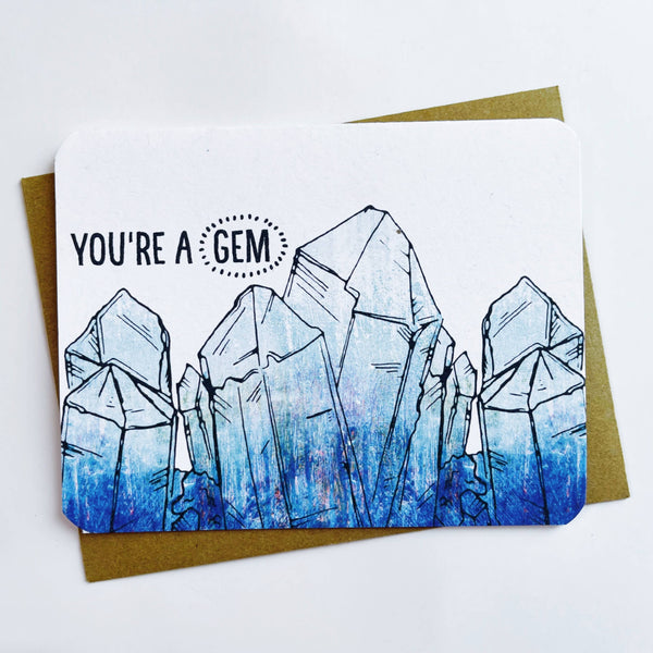 A greeting card has blue crystals along the bottom. The text on the card reads "you're a gem."